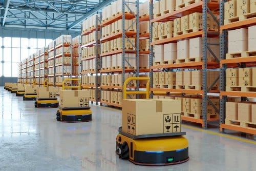 Autonomous mobile robots carrying boxed orders along the aisles of a racked warehouse