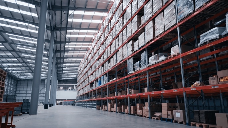 A long warehouse aisle lined with racking and stacked pallets