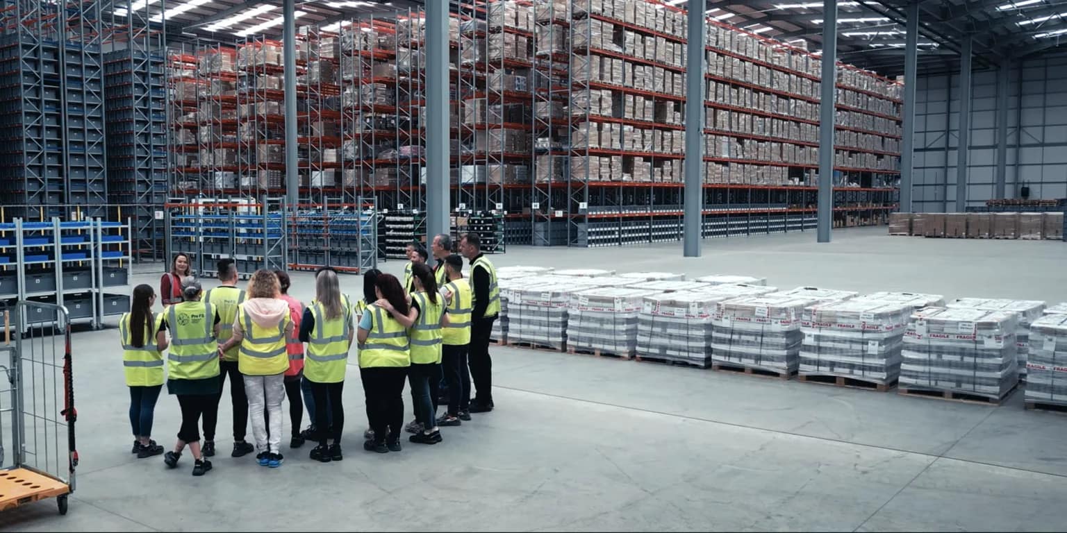 Fulfilment operatives walking between racking, picking orders with handheld scanners