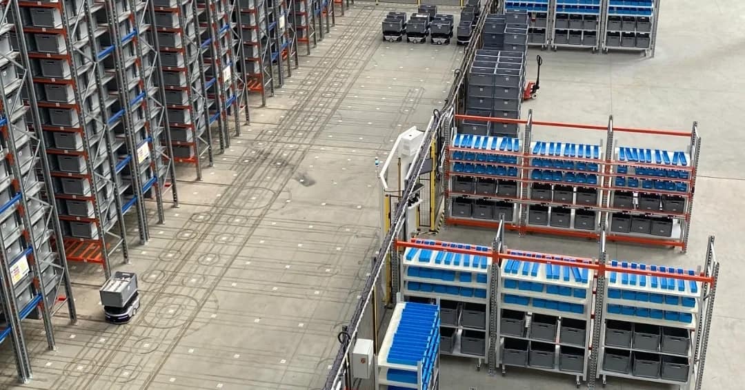 Automated warehouse shelving with robot arm retrieving a boxed parcel