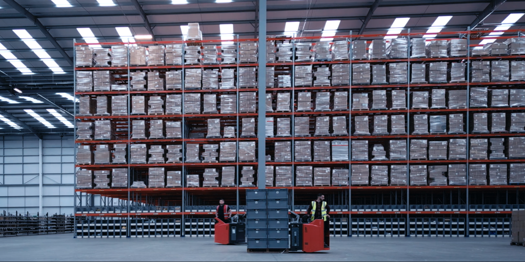 A modern third party fulfilment warehouse with operators manoeuvring fork lift trucks